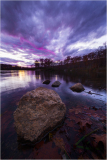 Serene waters brushed with stormy cloaked hues as evening friends gather on eclectic banks.