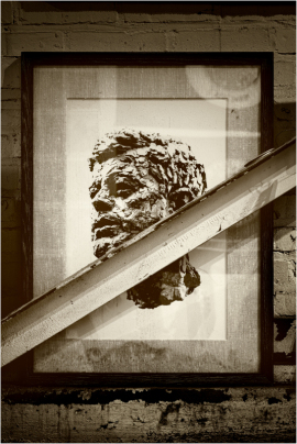 A striking sculpture's portrait framed, with shadows and light playing across it.
