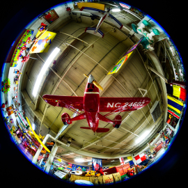 A red model airplane suspended in a colorful, vibrant indoor setting.