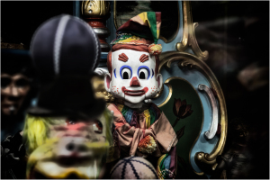 A haunting clown figure surrounded by shadows and colorful decor.