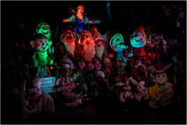 A vibrant, eerie gathering of colorful puppets and dolls in dim light.