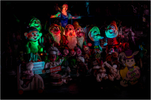 A vibrant, eerie gathering of colorful puppets and dolls in dim light.