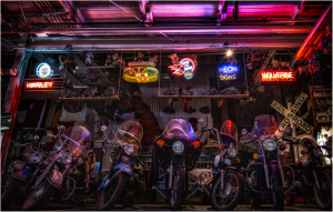 Vintage motorcycles under a vibrant neon glow in a dimly lit garage.