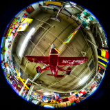 A red model airplane suspended in a colorful, vibrant indoor setting.