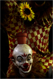 A clown's head with a sunflower pot, set against a checkered backdrop.