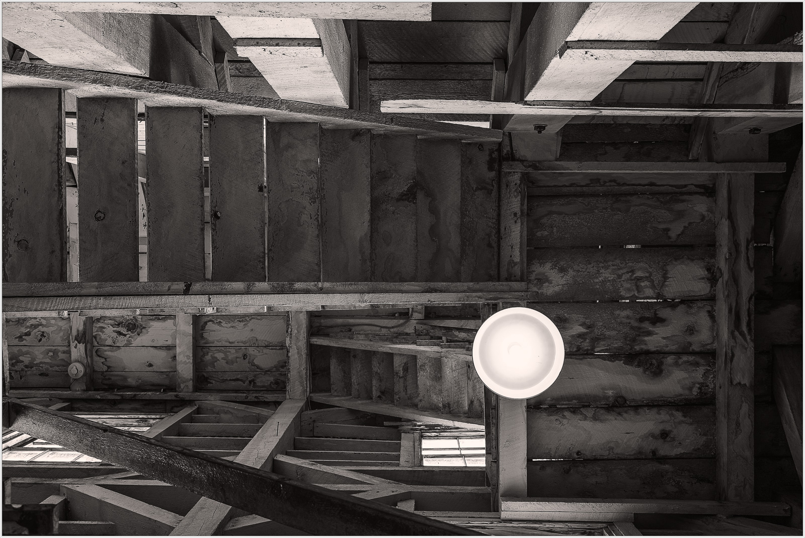 A view of worn wooden stairs leading down into a dimly lit space, showcasing structural decay.