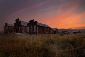 Historic wooden buildings in Bodie at sunset, showcasing ghost town remnants.