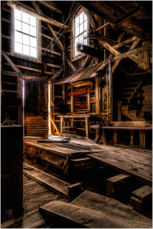 Interior of a historic building with wooden beams and stairs, showcasing early construction techniques.