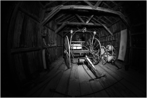 Historic wagon inside a wooden structure, showcasing early transportation methods.
