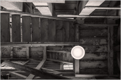 A view of worn wooden stairs leading down into a dimly lit space, showcasing structural decay.