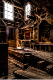 Interior of a historic building with wooden beams and stairs, showcasing early construction techniques.