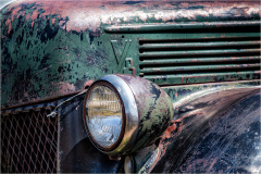 Close-up of a weathered vintage truck's front, showcasing its rust and aged features.