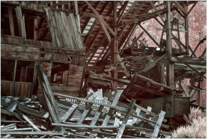 A decaying structure, its timbers twisted and forlorn, lies in ruin.