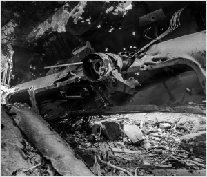 A close-up of a rusted car interior, with wires and debris scattered around.