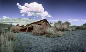 A dilapidated structure lies amidst desolate terrain under an ominous sky.