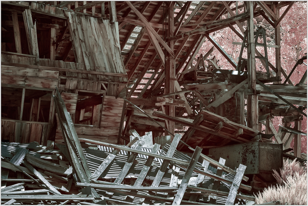 A decaying structure, its timbers twisted and forlorn, lies in ruin.