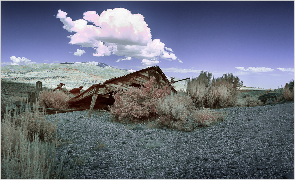 A dilapidated structure lies amidst desolate terrain under an ominous sky.