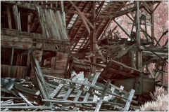A decaying structure, its timbers twisted and forlorn, lies in ruin.