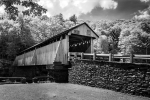 Old covered bridge stands against a bleak landscape; dark clouds loom above.