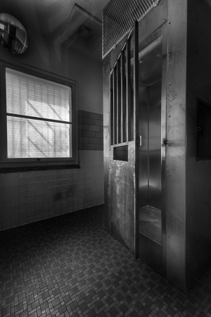 Interior view of a vintage elevator shaft with metal door and tiled floor.