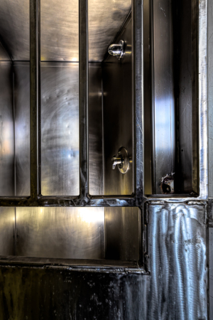 Interior view of a metallic cell with bars and fixtures, emphasizing stark design elements