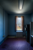A small blue room with a single window and light brown curtains.