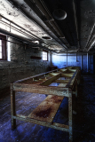Abandoned industrial space with a long, rusted table under dim lighting