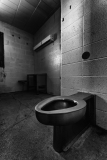 Interior view of a dimly lit restroom with a wall-mounted toilet and minimal furnishings.
