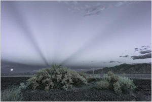 A surreal landscape in Death Valley, shadows stretching across the desert under a twilight sky.