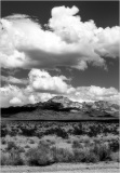 A vast desert landscape under a dramatic sky filled with clouds.