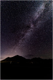 A vast night sky filled with stars and the Milky Way over dark mountains.