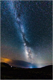 A vast night sky filled with shimmering stars and the Milky Way stretching across the horizon.
