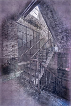 Interior view of a staircase in an industrial building with brick walls and metal railings.