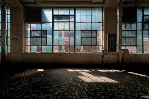 A sunlit room with shattered windows casting fragmented shadows on the floor.