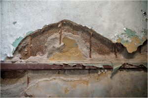 Textured wall with peeling paint and exposed layers, showcasing decay and age.