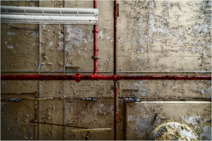Rusty pipes intersecting with peeling walls; a testament to forgotten labor.