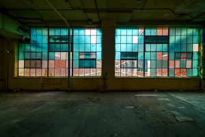 An eerie view of stained windows illuminating a desolate space, shadowy and forsaken.