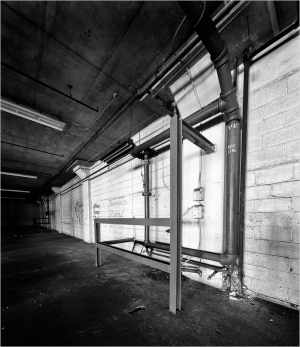 Abandoned concrete interior with rusted pipes and peeling paint