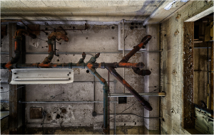 View of an industrial ceiling with exposed pipes and ductwork.