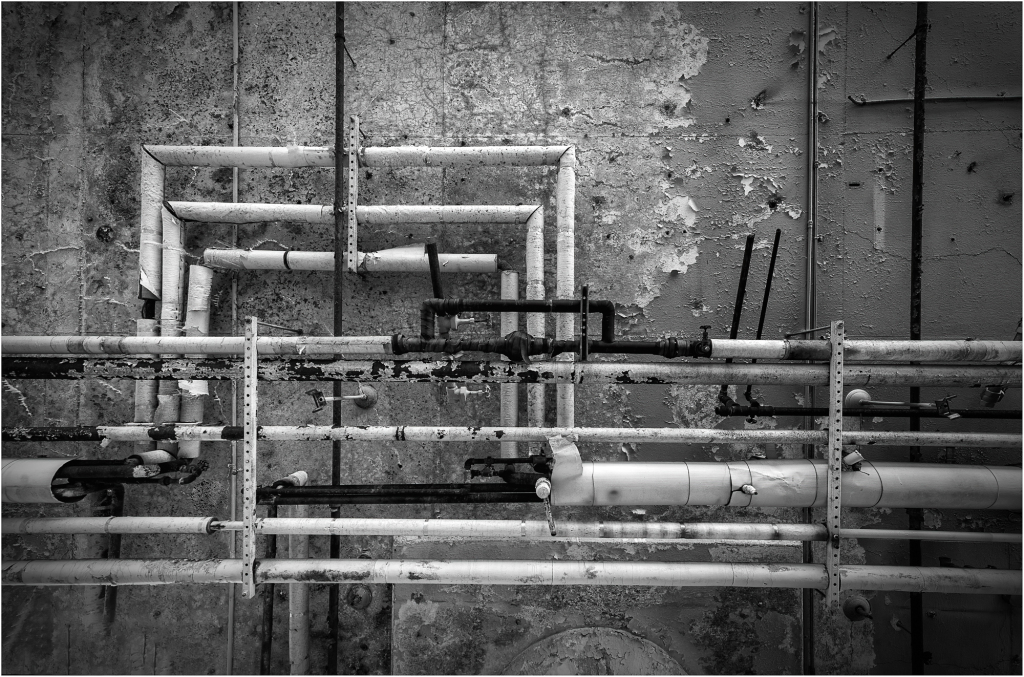 Black and white pipes against a rough wall