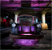An old truck bathed in surreal purple light, surrounded by industrial shadows.