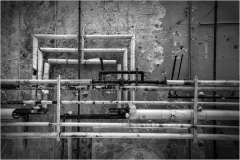 Black and white pipes against a rough wall