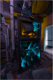 An enigmatic machine cornered in vibrant blues and grimy shadows.
