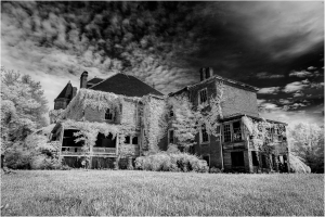 A spooky, overgrown mansion draped in vines under a dramatic sky.