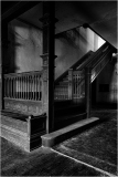 An empty stairwell casts shadows deep and long, a stillness cloaked in whispers of the past.