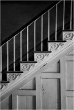 A worn staircase with ornate railings leads to the unknown above.