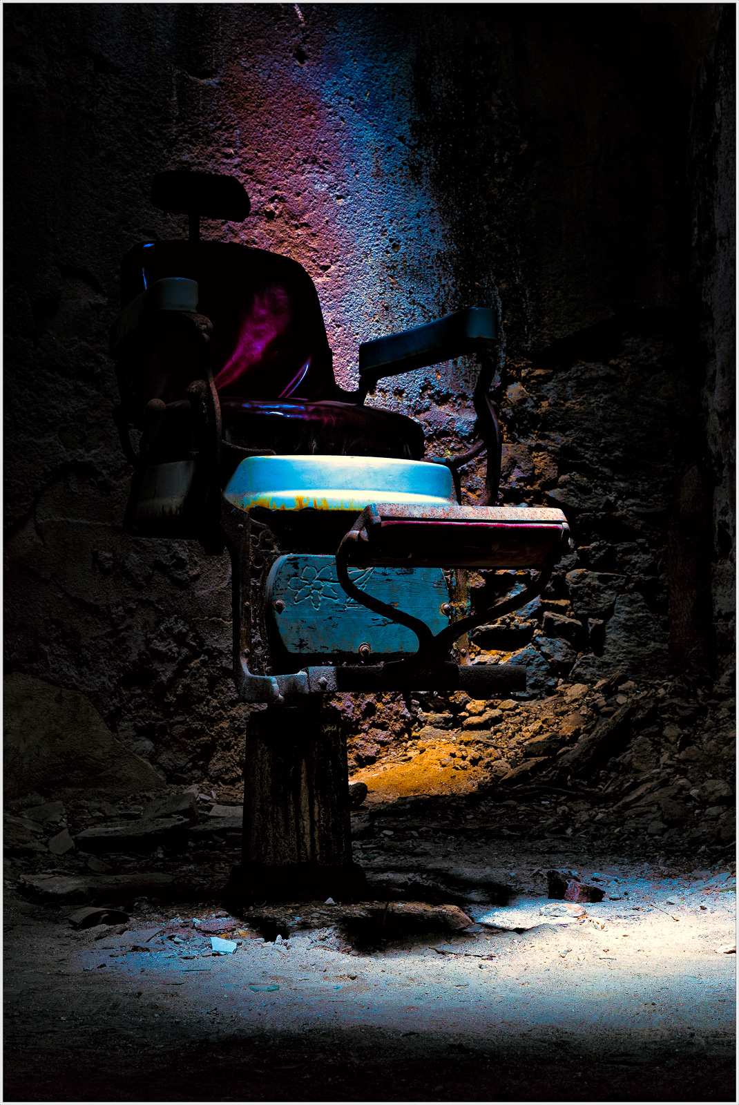 An old dental chair in a dimly lit room with colorful lighting.