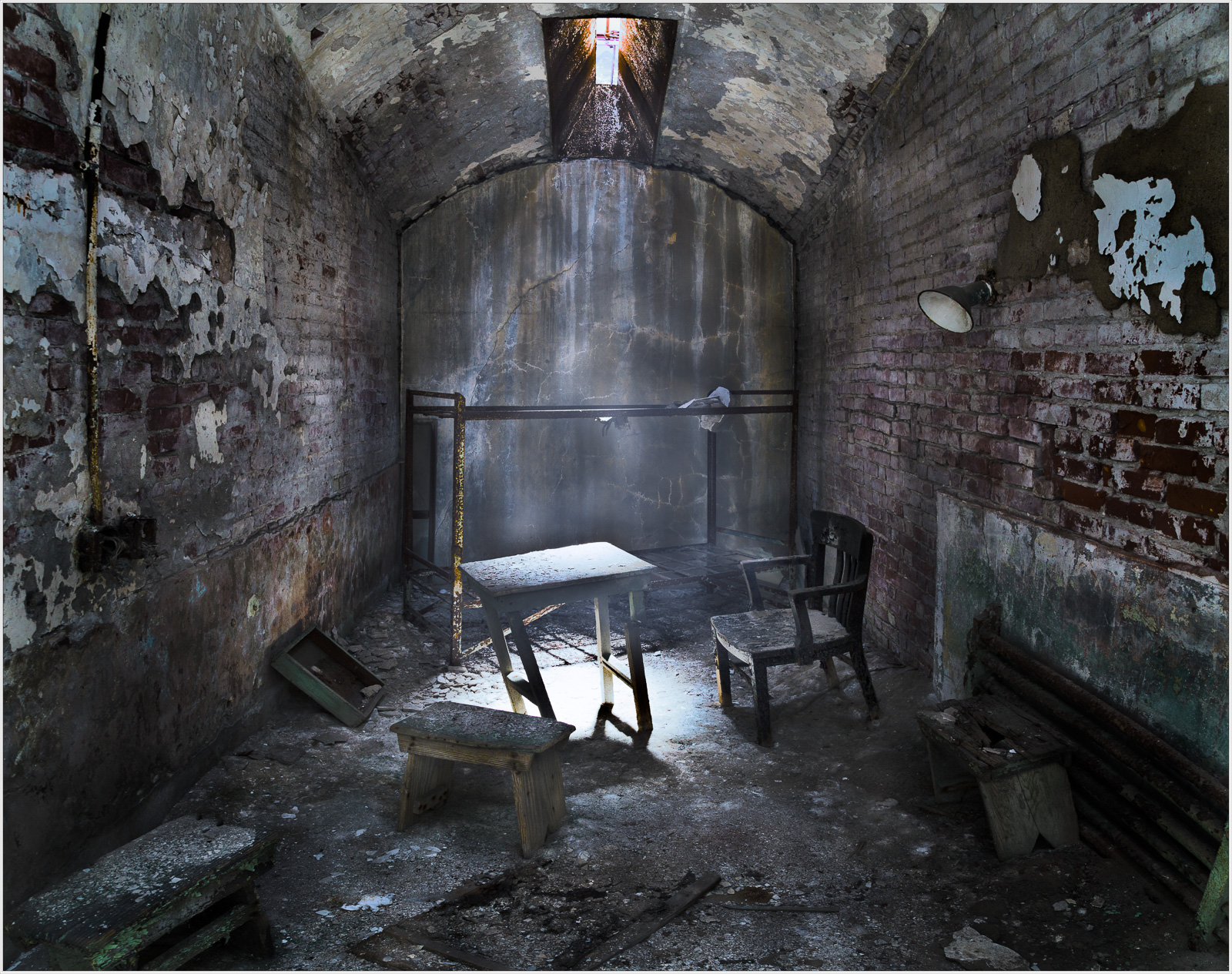 An abandoned room with a table and chair, dimly lit by a shaft of light.