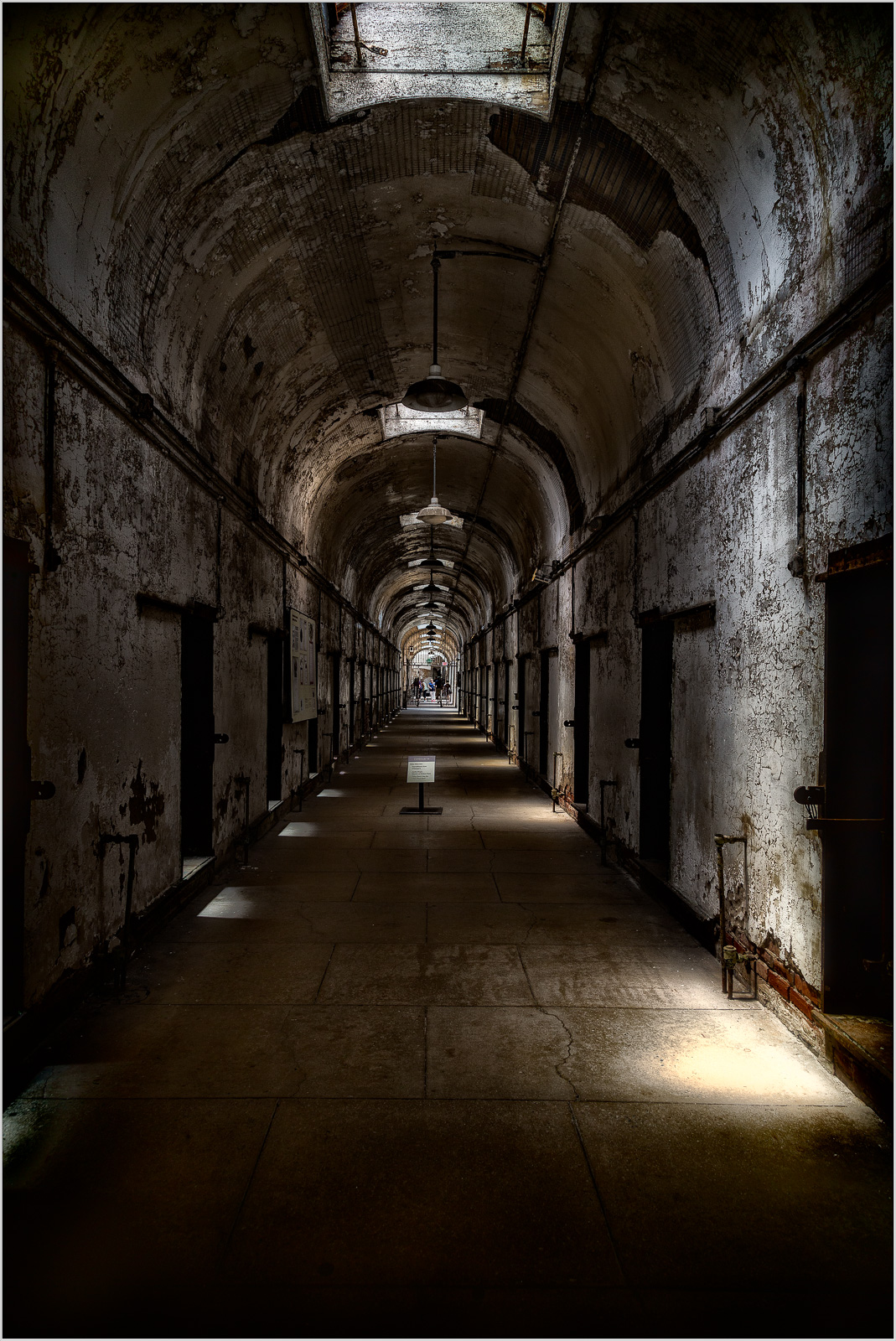 Dimly lit corridor in an old prison with peeling walls and doors on either side