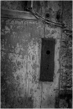 A close-up of a weathered wooden door with a chain and a keyhole.